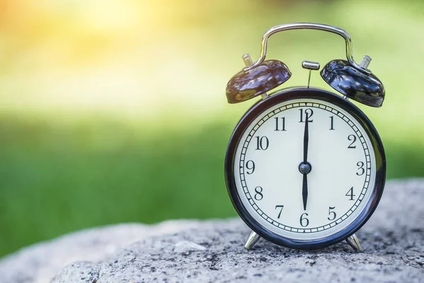 Reloj en el fondo verde de la naturaleza, hora del reloj de campana retro a las 6 en punto . — Foto de Stock