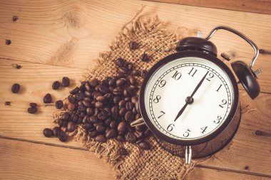 Arabica kahve çekirdeği çuval ve ahşap arka plan masada retro saatiyle 06: 00.