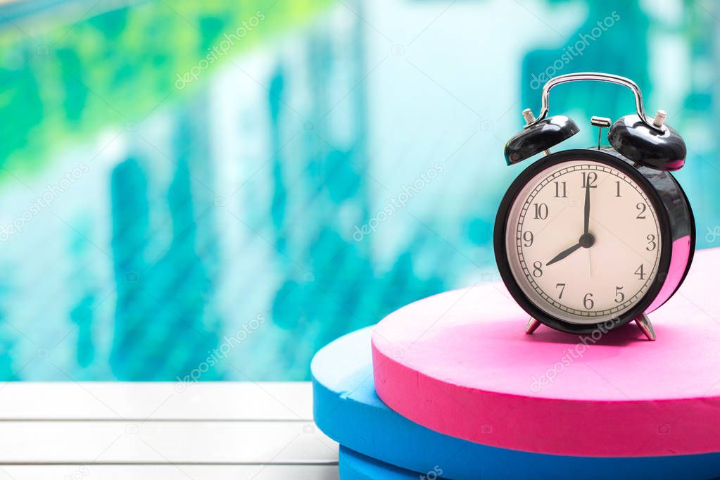 swimming times, retro black bell clock time at 8 o'clock at swimming pool blur background.