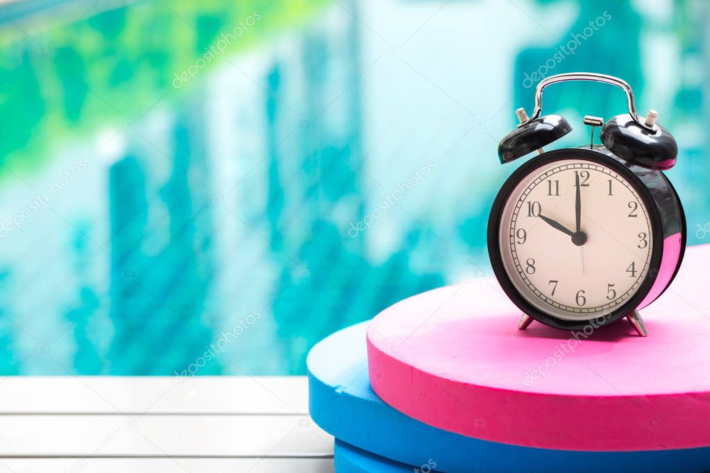 swimming times, retro black bell clock time at 10 o'clock at swimming pool blur background.