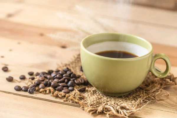 Аромат горячий черный кофе или американо и арабика кофейных зерен с дымом на деревянном фоне . — стоковое фото