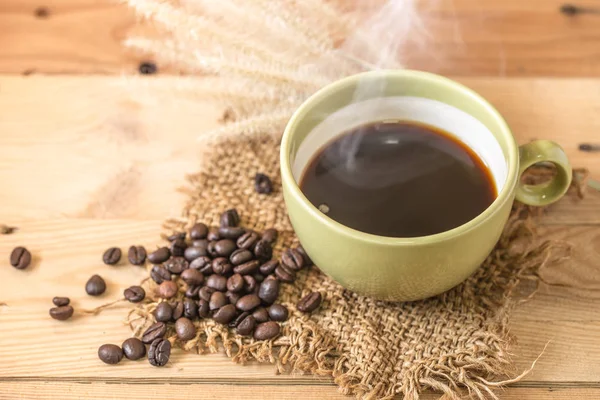 Аромат горячий черный кофе или американо и арабика кофейных зерен с дымом на деревянном фоне . — стоковое фото