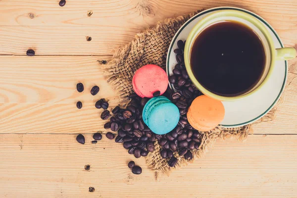 macarons tatlı ahşap arka plan üzerinde siyah kahve.