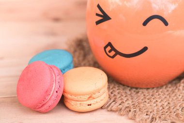 macarons tatlı güzellik tatlı gülümseme kırışıklık yüz kupa üzerinde tahta arka plan pembe renk tonu ile.