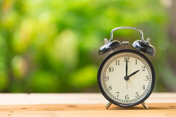 Klok op houten tafel in de groene tuin tijd om 2 uur — Stockfoto