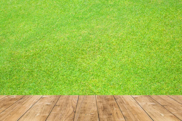 Деревянный пол с деревянным полом на зеленом фоне травы . — стоковое фото