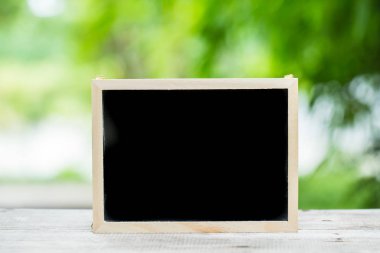 metin yeşil doğa arka plan ile ahşap masa üzerinde için boş kara tahta yer