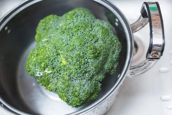 Limpar a água com lavagem de legumes brócolis na cozinha . — Fotografia de Stock