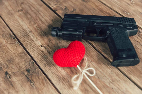 Silah tabanca ve ahşap arka plan üzerinde kırmızı kalp sevmek — Stok fotoğraf