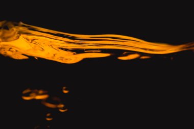 Altın sıvı yağ sıvı su siyah arka plan üzerine yansıtmak.