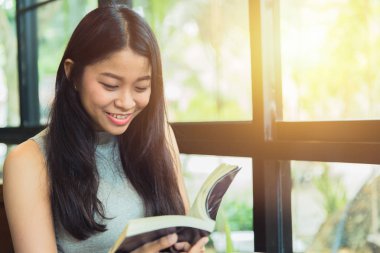 Zevk kez kitap okumak, kahve dükkanı vintage renk tonu kitapta Asyalı kadınlar Taylandlı teen gülümsemeyle ile rahatla