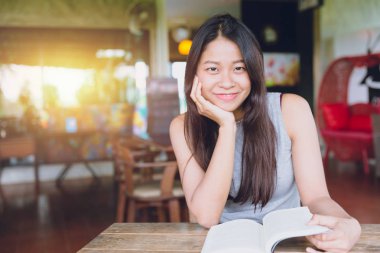 Zevk kez kitap okumak, kahve dükkanı vintage renk tonu kitapta Asyalı kadınlar Taylandlı teen gülümsemeyle ile rahatla