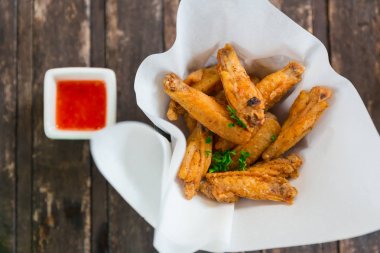 Çıtır tavuk kanadı. Tay tarzında kızarmış meze veya kırmızı biber biber lezzet ve acı baharatlı sos aperatif yiyecek gıda yağ emici kağıt üzerinde ahşap masaya servis.