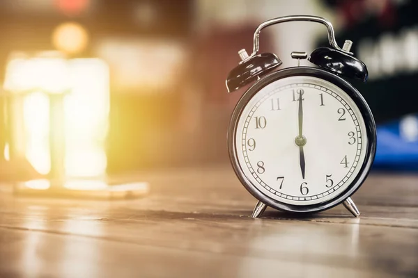 Reloj retro de las 6 en punto sobre mesa de madera con fondo de luz solar —  Fotos de Stock