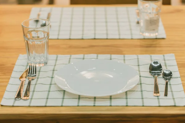 clean new modern lunch setting with silver cutlery in napkin for meal on wood table.