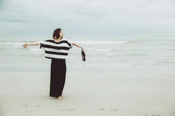 Libertad de las mujeres concepto de viaje único. Chica libre brazo abierto emoción lenguaje corporal en el mar playa vintage tono de color . — Foto de Stock