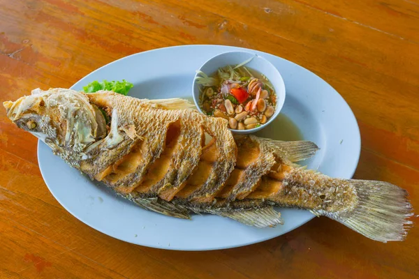 Тайская рыба из морепродуктов во фритюре с острым соусом подается на деревянном столе . — стоковое фото