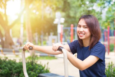 Genç Asyalı gülümseme zevk parkta göğüs egzersiz sağlıklı, kadınlar egzersiz için açık.