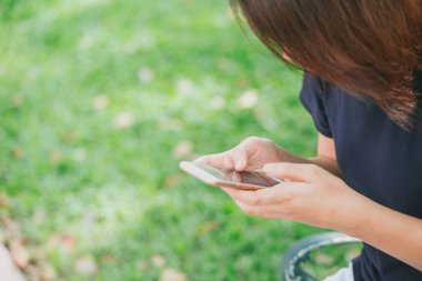 parkta Smartphone ya da metin sohbet kullanarak Asya siyah saçlı kadın