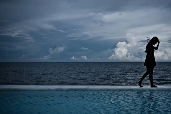 Deniz okyanus arka plan ile bir kadın Woking siluet gölge.