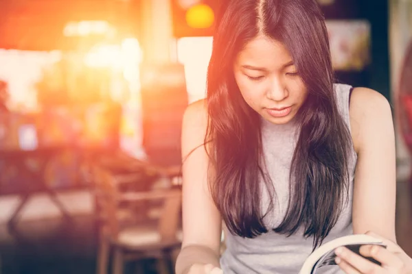 Aproveite os tempos de relaxamento com livro de leitura, mulheres asiáticas adolescente tailandês foco sério para ler livro de bolso no café no tom de cor vintage manhã — Fotografia de Stock