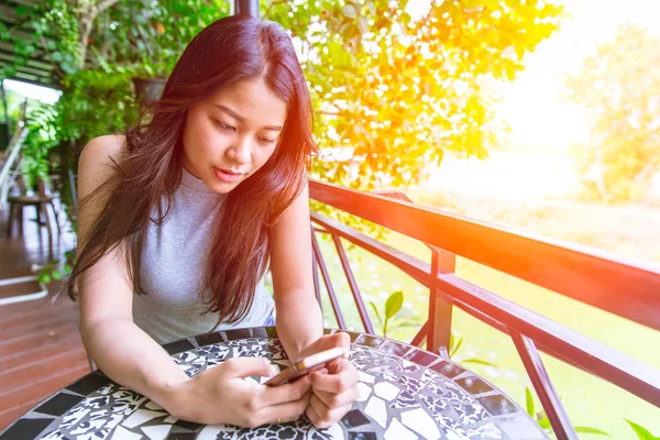 Aziatische vrouwen ontspannen om te spelen en kijken naar smartphone scherm met natuur sunset achtergrond. — Stockfoto