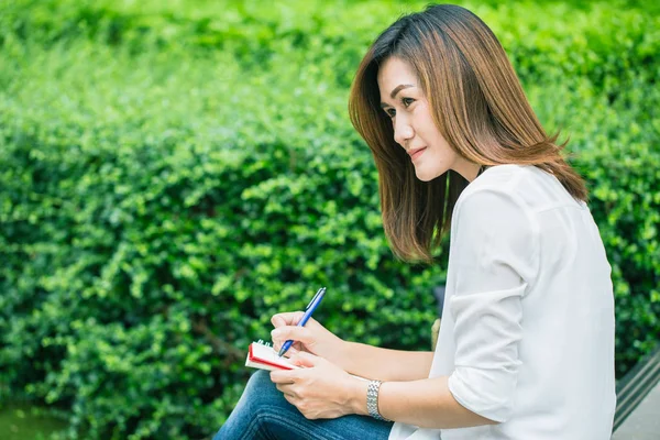 Mujeres que trabajan escribiendo en el parque, mujeres que trabajan al aire libre trabajo trabajo escritor de trabajo escribir texto en cuaderno . — Foto de Stock