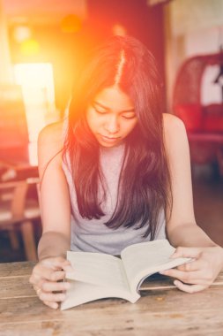 Zevk kez kitap okumak, kahve dükkanında sabah vintage renk tonu cep kitabı okumak için Asyalı kadınlar Taylandlı teen ciddi odak ile rahatla