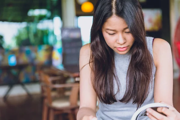 Disfrute de momentos de relax con libro de lectura, las mujeres asiáticas tailandesas adolescente enfoque serio para leer libro de bolsillo en la cafetería en el tono de color vintage de la mañana — Foto de Stock