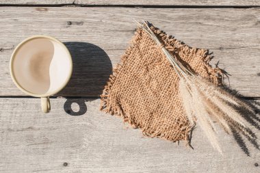 Boş kahve fincanı ile ahşap arka plan, hipster yaşam tarzı konsepti olan torba çimen çiçek.