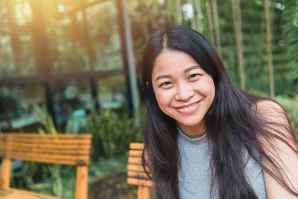 Porträtt asiatiska kvinnor svart långt hår vuxen lyckligt leende njuta i trädgårdscaféet med plats för text. — Stockfoto