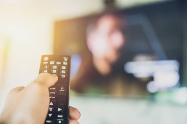 elini tut akıllı Tv uzaktan kumanda bir televizyon bulanıklık arka plan ile. izlerken program kanalı değiştirmek
