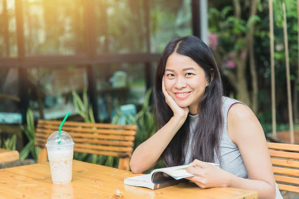 Asian women with book in garden with coffee shop.