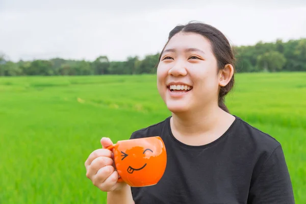 Asian Teen fat women laugh and hold mug with green nature background good wheatgrass drink concept