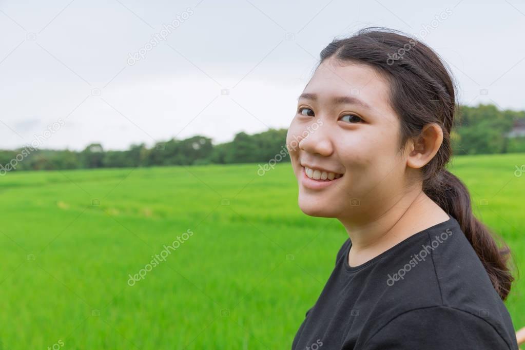 cute young innocent asian teen smile with green rice field in asian countryside nature background