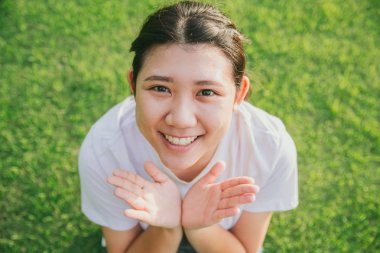 sevimli genç masum Asya teen gülümseme yeşil çim arka plan ile