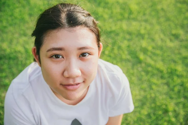 Söt ung oskyldig asiatisk teen smile med grönt gräs bakgrund närbild huvud och ansikte — Stockfoto