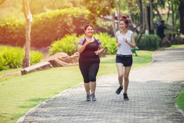 Two Asian girls fat and thin friend running jogging in the Park