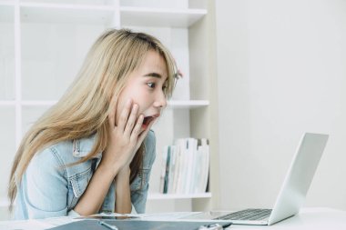 Laptop ekranına bakıp iyi haber konsepti için şok edici şeyler gördüğünde şaşırmış ve şaşırmış bir ifade kızı gibisin..