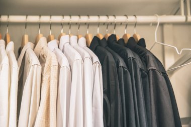 Erkekler iş gömleklerini dolaba asıyor. Renk tonunda..