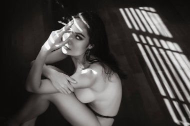 Pencerenin önünde sigara içen seksi kadın siyah beyaz resim monotonluğu yapıyor..