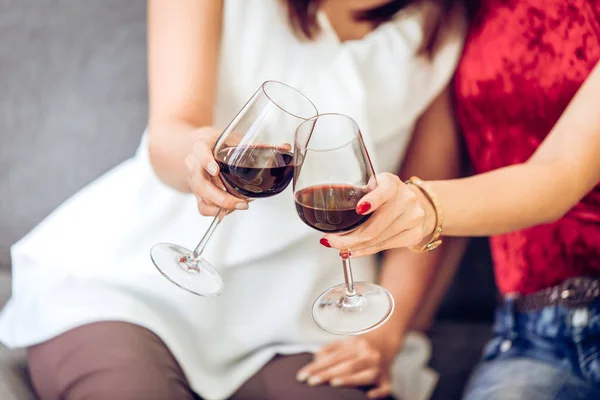 people drinking red wine hand clink glasses together in party.