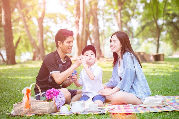 Genç bir aile çocuk ile oynuyor açık hava parkında sevimli bir hayat sürüyor ve doğayla iç içe yaşıyor.