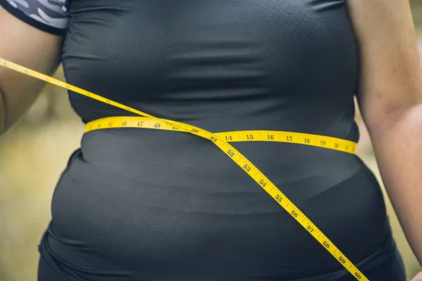 girl waist belly fat woman with waist tape measure closeup shot.
