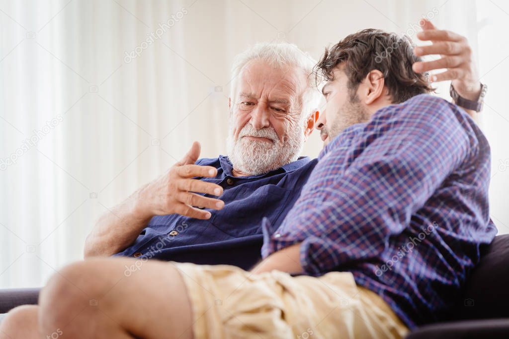 old man serious discussion with younger man indoor, grand father serious talking with his son at home.