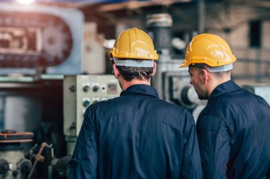 Makine servisi birlikte konuşuyor. Fabrika arka görünümünde çalışan takım çalışması..