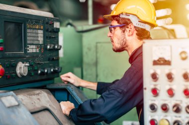 Genç meslek teknisyeni, fabrikadaki otomatik Cnc 'ye ağır makine çalıştırıyor..