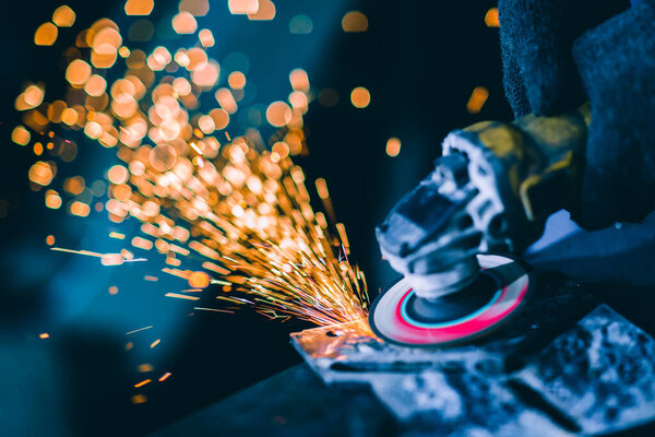 Крупный план тяжелого сталевара с помощью электрического колеса шлифовальный диск резки металлической пластины в рабочем месте Опасность огня свет искры от инструмента
.