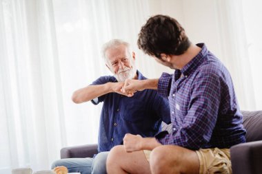Bir adam, büyükbabasıyla, büyükbabasıyla ya da yaşlı bir adamla el sıkışır. Oğluyla el ele tutuşur..