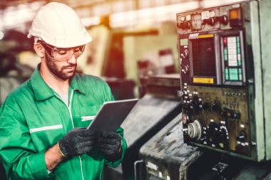 Yeşil eko işçisi enerji tüketimini kontrol ediyor. Ağır endüstri fabrikasında çalışıyor. Yeşil renkli güvenlik giysisiyle..